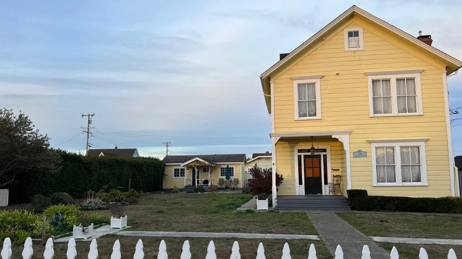 ADU in real estate — a two-story pitch-roof house with a small one-story ADU in the back