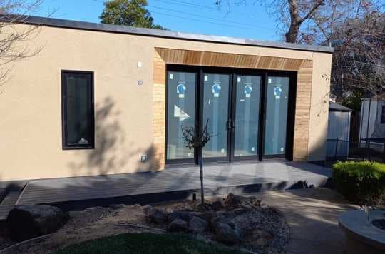 ADU with big patio door, dark window frames, wood plank accents and stucco exterior