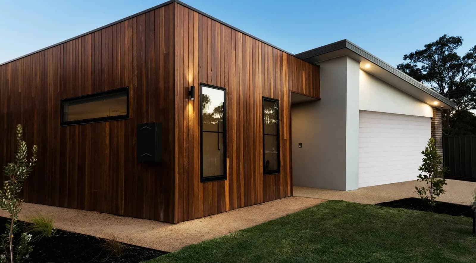 Modern wood-clad house with an attached garage at dusk
