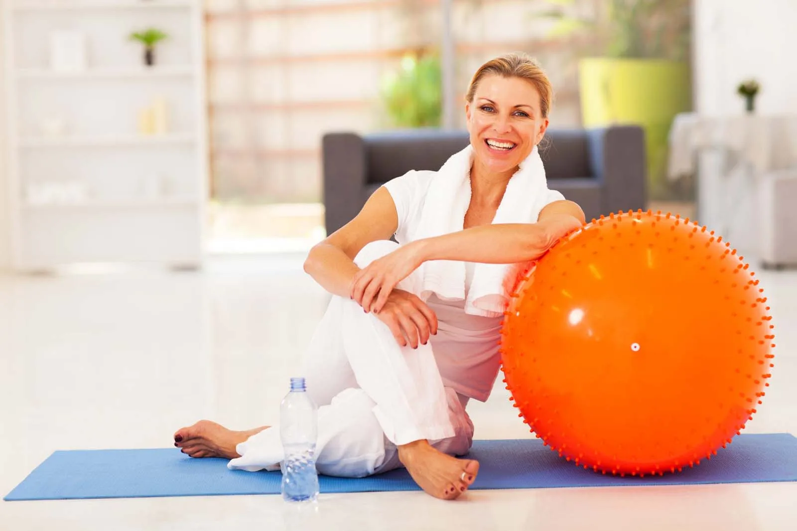 Person exercising with an orange stability ball in a bright studio space