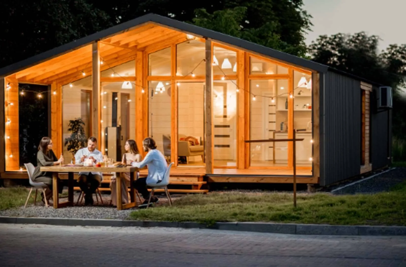 Prefab ADU home at dusk with a family dining under string lights